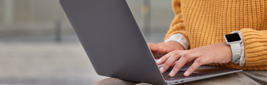 Someone typing on a gray laptop